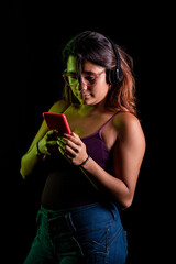 Mujer latina escuchando música con auriculares y un celular rojo en fondo negro