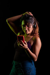 Mujer latina escuchando música con auriculares y un celular rojo en fondo negro