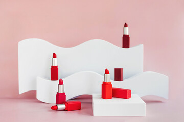 Mockup of red lipsticks on a white staircase with geometric shapes and a podium. Background for branding and packaging presentation. Beauty and makeup product concept