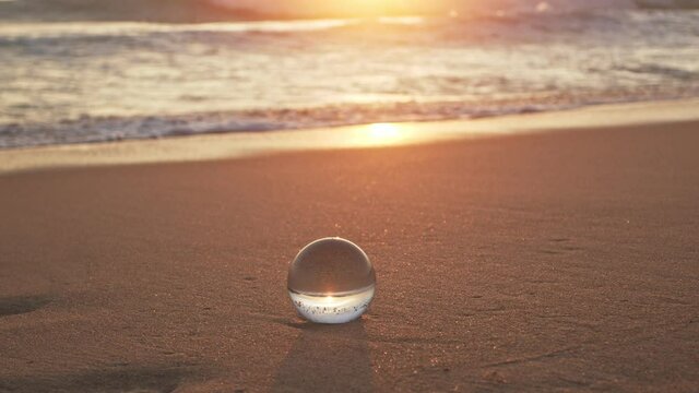 The natural view of the sea and sky in beautiful sunset are unconventional and beautiful inside crystal ball. .A image for a unique and creative travel idea.