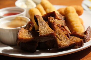 Fast food, Fresh beer snacks assortment. fried rye bread croutons and cheese sticks with sauces, beer plate in the cafe. Very shallow focus