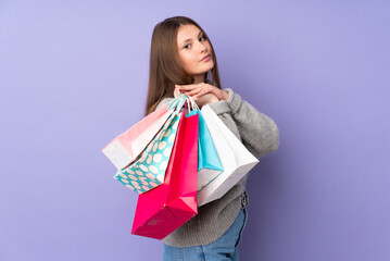 Fototapeta na wymiar Teenager caucasian girl isolated on purple background holding shopping bags