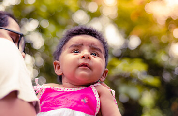 Mother holding infant baby girl close to her, three months old cute baby dressed in pink clothes in the garden evening. Mother's most precious gift concept.