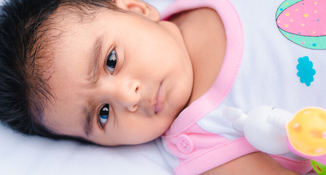 Cute 3 months old baby girl looking at the camera, curious facial expressions, and eyebrows close up photograph.