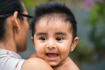 Smiling cute baby on the mother's shoulders. The adorable smile on the 5 months old baby girl's face.