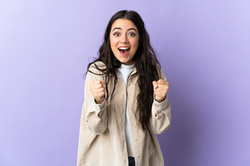 Young caucasian woman isolated on purple background celebrating a victory in winner position