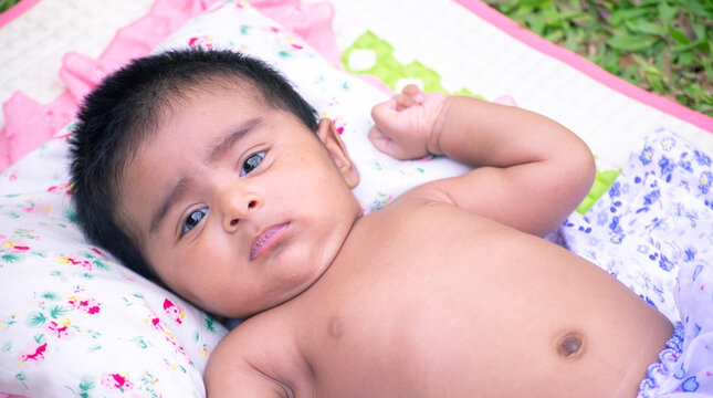 Cute baby girl Lying on the soft blanket sheet on the green grass. playtime for the five months old kid in the home backyard in the morning. concept of a free and relaxed child.