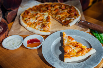 Homemade pizza on brown paper on wooden table with green leaf and white cream