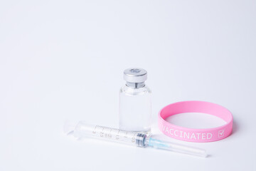 vials of medicine/vaccine, syringe and rubber wrist band with "VACCINATED" text in it
