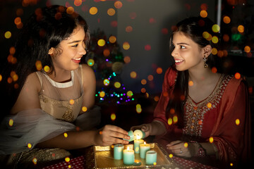 Portrait of two Indian woman holding diyas and lamps on the festive occasion of Diwali. Celebrations at home