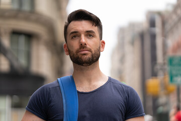 Fototapeta premium Young caucasian man on city street walking serious face