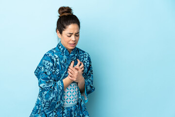 Woman wearing kimono over isolated background having a pain in the heart
