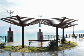 Empty benches in the gazebo on the embankment after the rain in the resort town Sudak, Crimea.