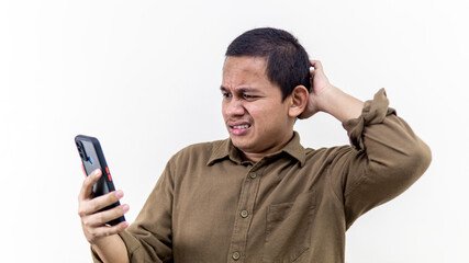 Confuse, thoughtful, doubtful and skeptical face expression of young Asian Malay man looking at the smartphone.