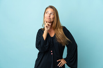 Middle age brazilian woman isolated on blue background thinking an idea while looking up