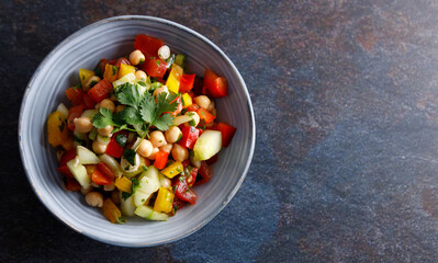 Homemade chickpea salad. Homemade healthy vegan salad, with chickpea , tomato, cucumber, paprika served in a bowl. Healthy meal, on a dinner table.