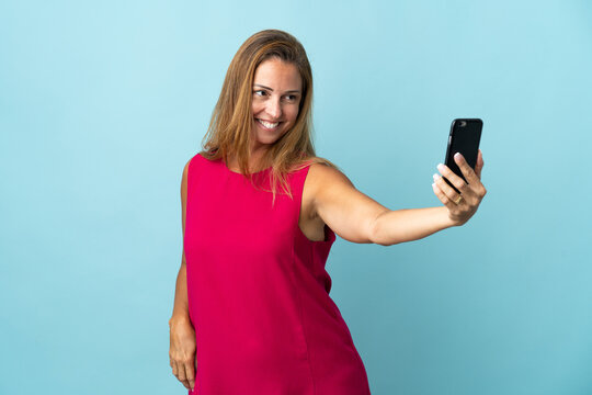 Middle age brazilian woman isolated on blue background making a selfie