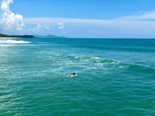 A young man surfer riding waves at Natai beach in Phang Nga, Thailand. Asian man catching waves in blue ocean. Surfing action water board sport.