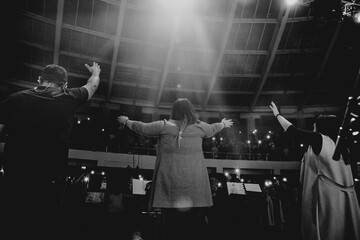 Christians raising their hands in praise and worship at a night music concert - obrazy, fototapety, plakaty