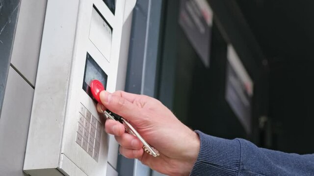 Male using intercom at residential building entrance. opens electronic code lock. man hand entering security system code, pressing button with index finger intercom device entrence door.