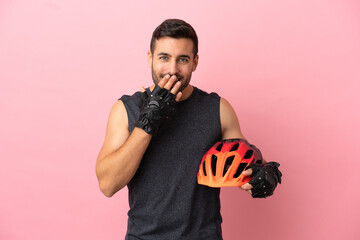 Young cyclist man isolated on pink background happy and smiling covering mouth with hand - obrazy, fototapety, plakaty