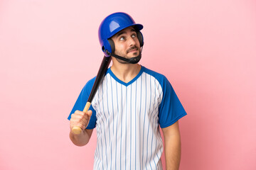 Baseball player with helmet and bat isolated on pink background thinking an idea while looking up