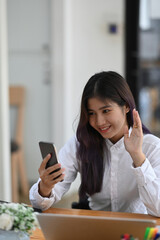 Cheerful female office worker having video call on mobile phone.