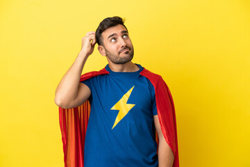 Young handsome caucasian man isolated on yellow background in superhero costume and having doubts © luismolinero