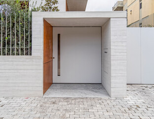 contemporary house front entrance with raw cement walls, white door and wooden side 