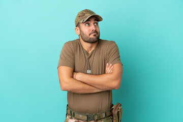 Military with dog tag over isolated on blue background making doubts gesture while lifting the shoulders