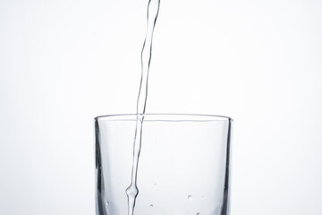 Jet of water or alcohol is pouring into a glass with splashes and bubbles, copy space