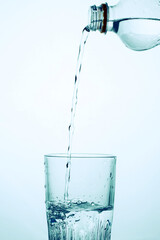 A man pours water from a transparent plastic bottle into a glass.