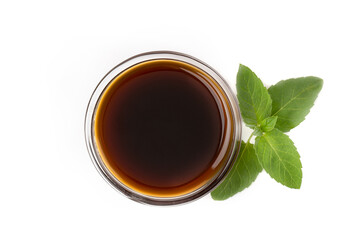 Dark caramel syrup or Soy sauce with green mint leaf, isolated on white background