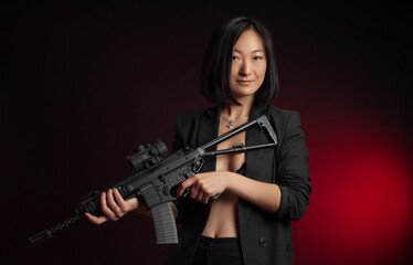 Fototapeta na wymiar asian woman in a jacket with an automatic rifle in her hands mafia fighter