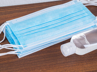 Medical face mask and hand sanitizer alcohol gel on brown  background. Concept of coronavirus...