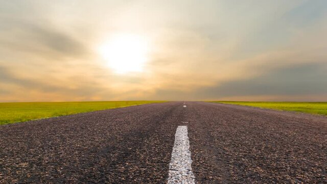asphalt road among green fields at the sunset time lapse scene