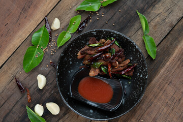 Moo ded deaw - deep fried dried pork with chilli and sriracha sauce isolated on the wooden table
