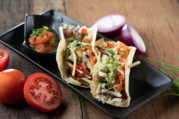 Slow cooked short ribs on tortillas with a spring onion tomato salsa isolated on wooden table