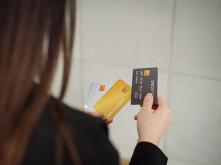 Close-up of three mockup credit cards in a businesswoman's hands, a rear view of a businesswoman in...