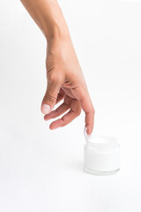 Woman moisturizing skin hand with cosmetic cream. Female hand touch glass jar of cream lotion. Beauty concept minimalism style.
