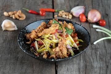 Somtam (Papaya Salad) with pork crackling isolated on rustic wooden table