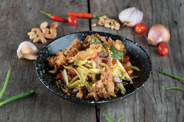 Somtam (Papaya Salad) with pork crackling isolated on rustic wooden table