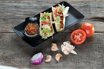 Slow cooked short ribs on tortillas with a spring onion tomato salsa isolated on wooden table