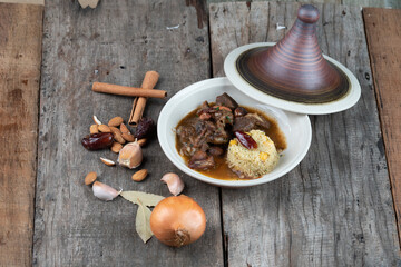 Slow cooked lamb with potato and dates served with warm couscous and chickpeas isolated on the wooden table