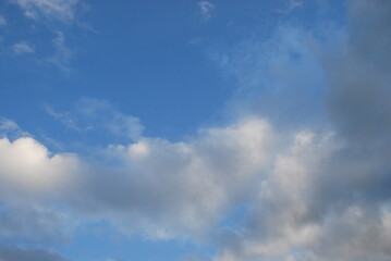 Multilevel clouds in the sky. In the light blue sky, clouds of different shapes and in different layers. Part of the clouds is white, part is gray from the shadow falling on them.