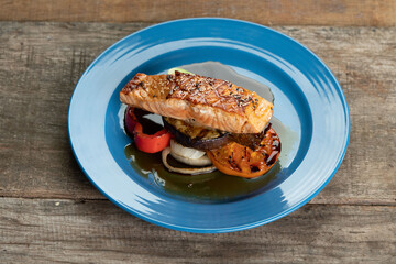 Grilled Salmon steak with vegetables isolated on rustic wooden table
