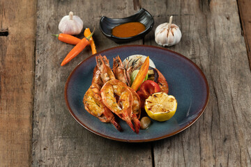 Wok-fried prawns with garlic and chili isolated on wooden rustic table