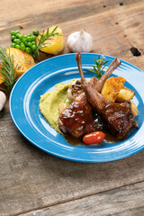 Two grilled lamb chops and potatoes served on pea puree with a mint sauce isolated on rustic wooden table