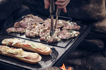 Man prepares a juicy pork neck with basil and barbecue spices and a baguette with tomato cheese and...