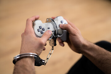 Video Game Addiction. Handcuffs and Gamepad